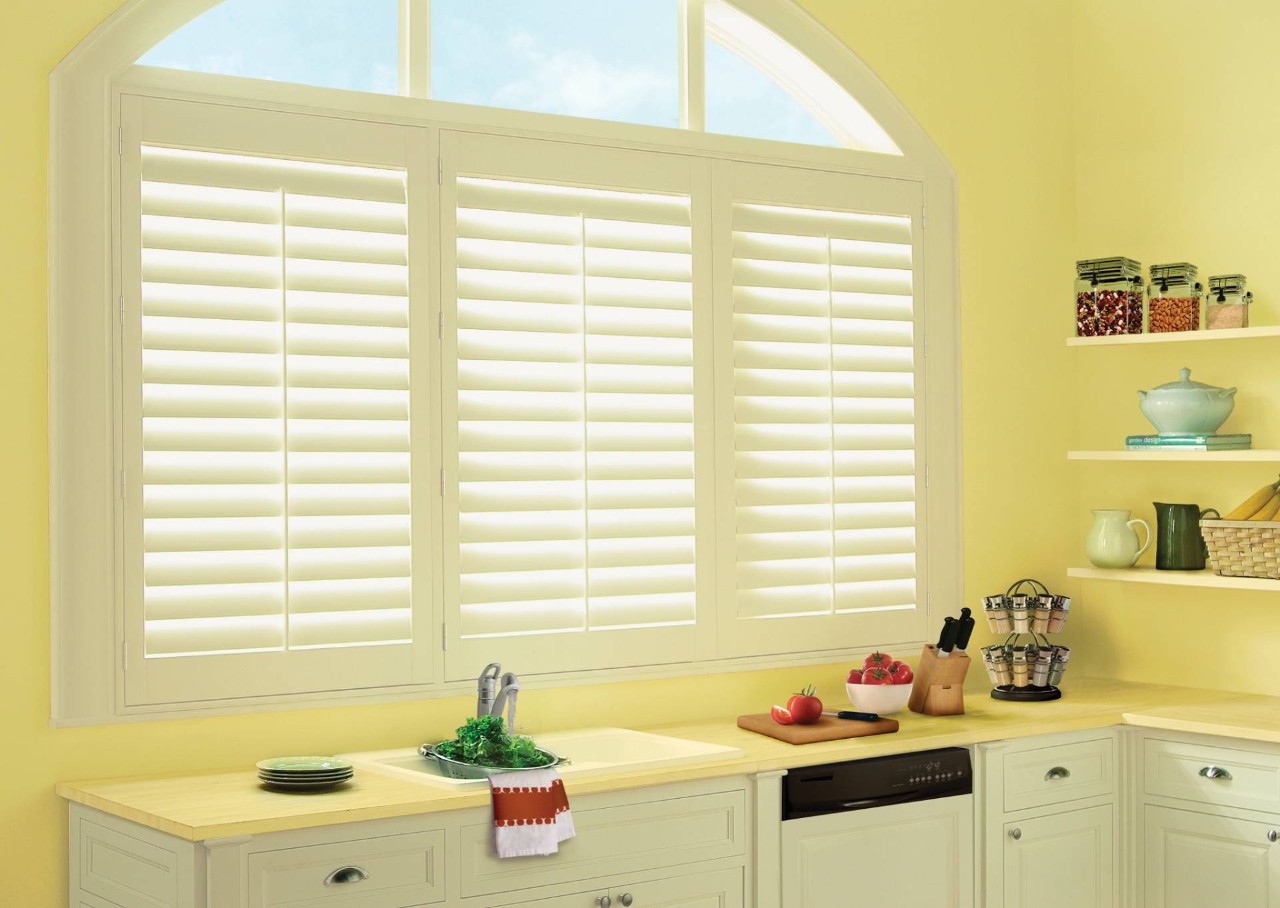 Hunter Douglas Palm Beach™ Polysatin™ Vinyl Shutters filtering light in a yellow Fairfax, VA, kitchen